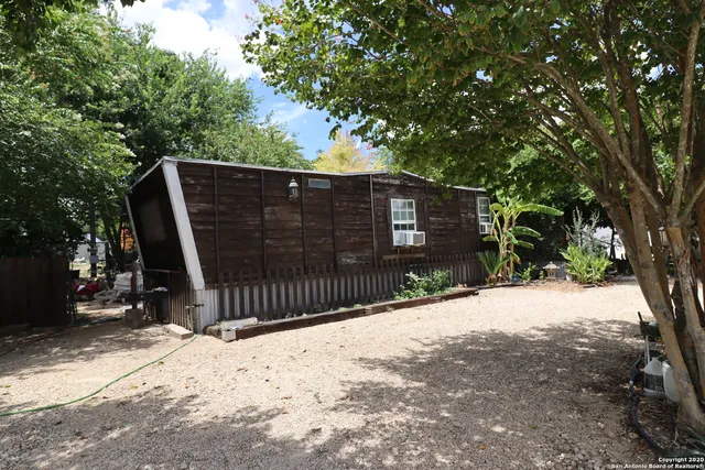 a view of backyard with wooden fence and a large tree