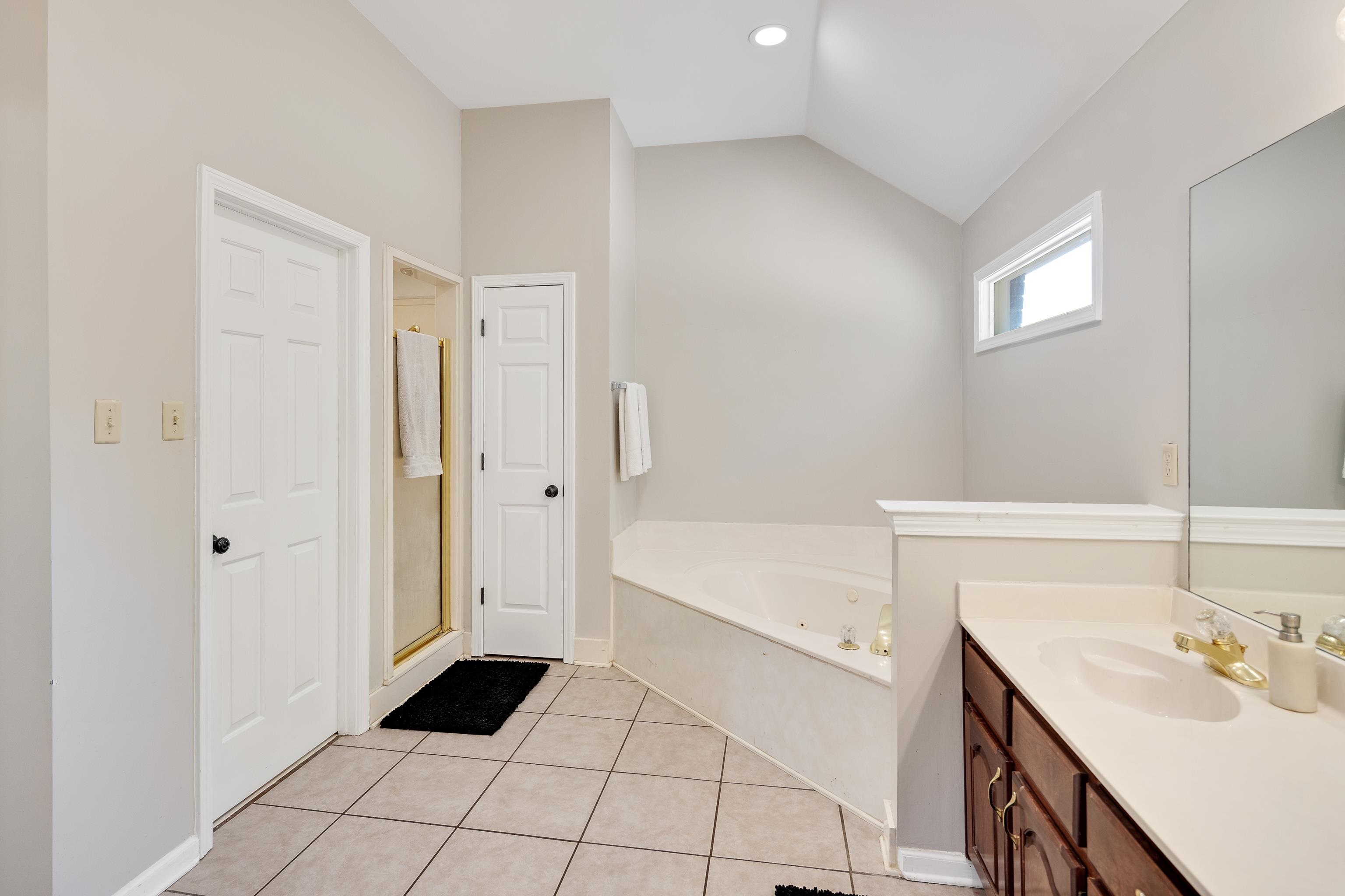 288 Hughes Cove Collierville, TN 38017 - Photo 19 of 31 Full bath with light tile patterned flooring, a whirlpool tub, vanity, lofted ceiling, and a shower stall