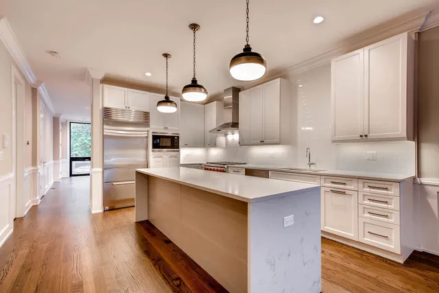 a kitchen with stainless steel appliances a sink a stove a refrigerator cabinets and wooden floor