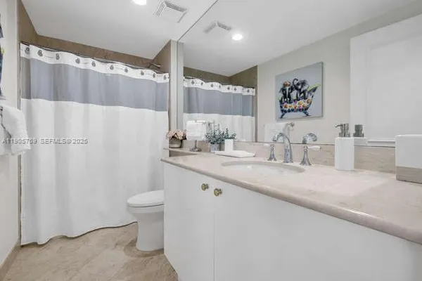 a bathroom with a granite countertop sink mirror vanity and toilet