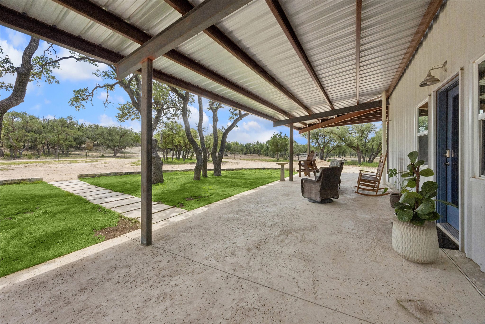 6411 West Fitzhugh Road Dripping Springs, TX 78620 - Photo 6 of 34 Covered concrete patio featuring an exposed beam metal roof structure and a white vertical siding exterior