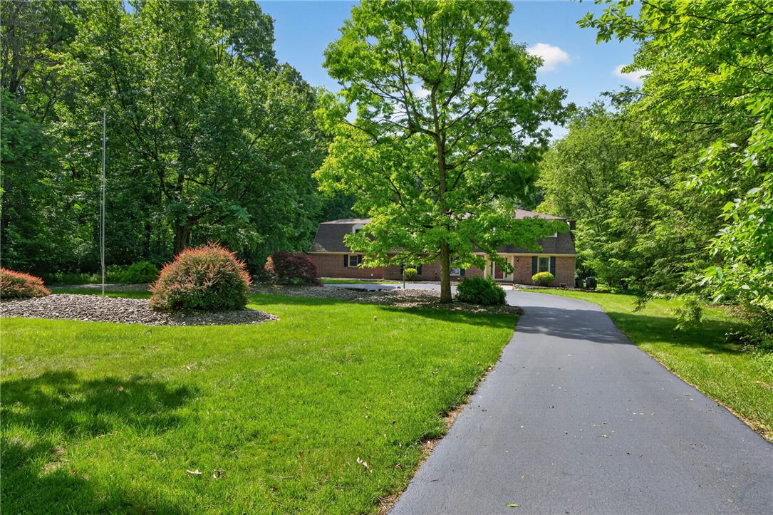1371 Stoke Park Road Bethlehem, PA 18017 - Photo 4 of 55 A winding asphalt driveway leads to a classic brick residence nestled among mature trees and manicured shrubbery.