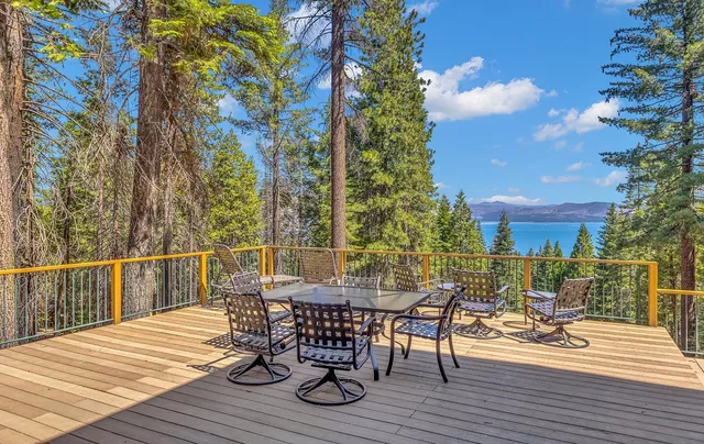 a view of a dinning table and chairs on deck with wooden floor and fence
