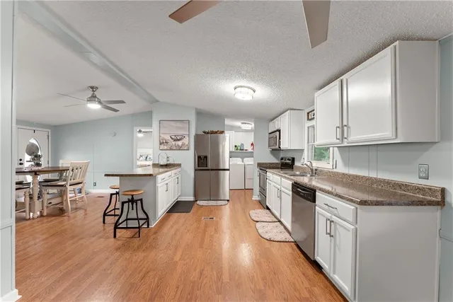 a kitchen with white cabinets stainless steel appliances and wooden floor