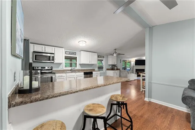 a kitchen with stainless steel appliances granite countertop a refrigerator a stove a sink dishwasher and white cabinets with wooden floor