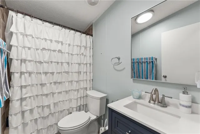 a bathroom with a sink a toilet and shower curtain