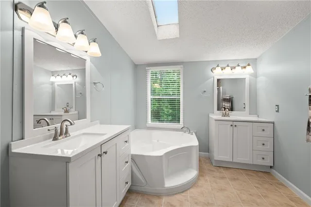 a spacious bathroom with a double vanity sink mirror and bathtub