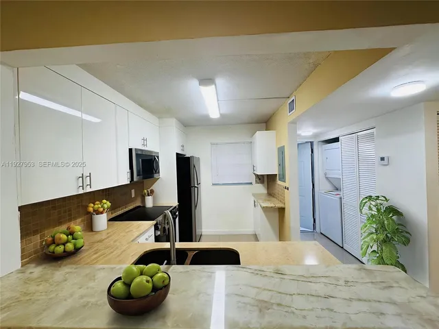 a kitchen with stainless steel appliances a sink and wooden floor