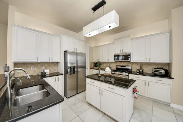 a kitchen with granite countertop a sink stainless steel appliances and cabinets