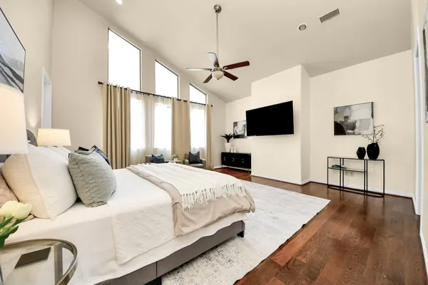 a bedroom with a bed a couch and a flat screen tv