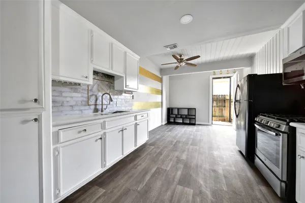 a kitchen with wooden floors appliances and cabinets