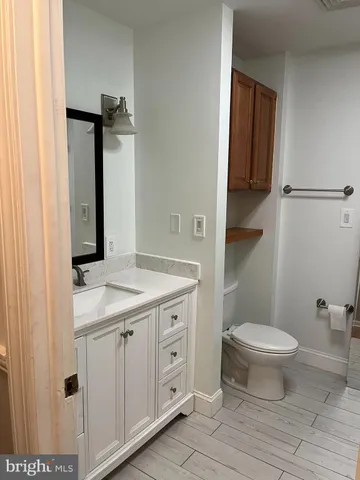 a bathroom with a granite countertop toilet a sink and a mirror