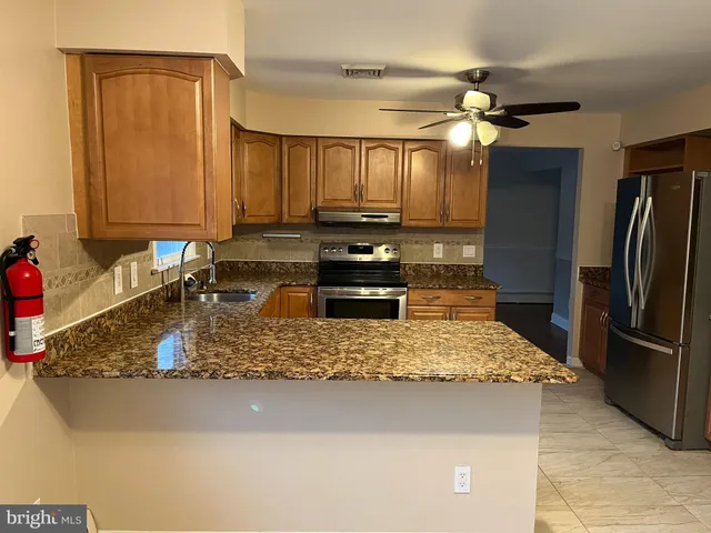 a kitchen with kitchen island granite countertop a refrigerator a stove a sink and dishwasher