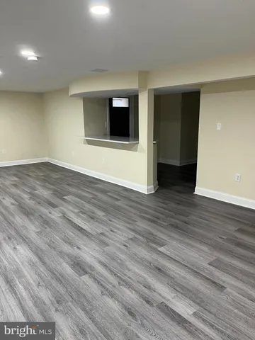 a view of an empty room with wooden floor and a fireplace