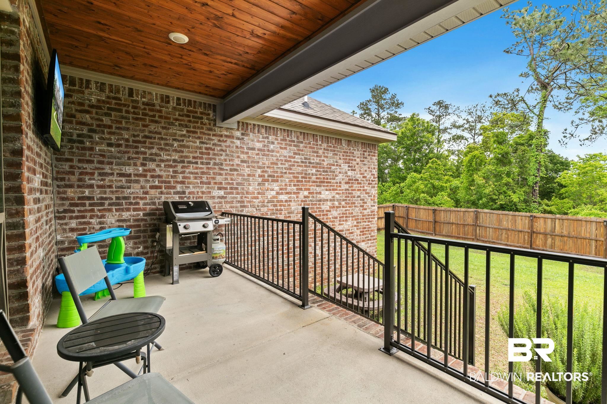 13233 Ibis Boulevard Daphne, AL 36527 - Photo 54 of 100 Covered outdoor patio featuring a wood-finish ceiling, brick exterior, concrete flooring, and black metal railings