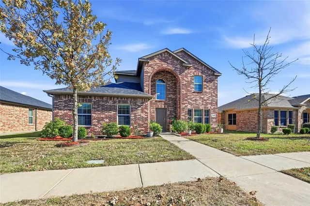 front view of a brick house with a yard