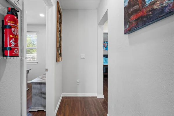 a view of hallway with wooden floor and a bathroom