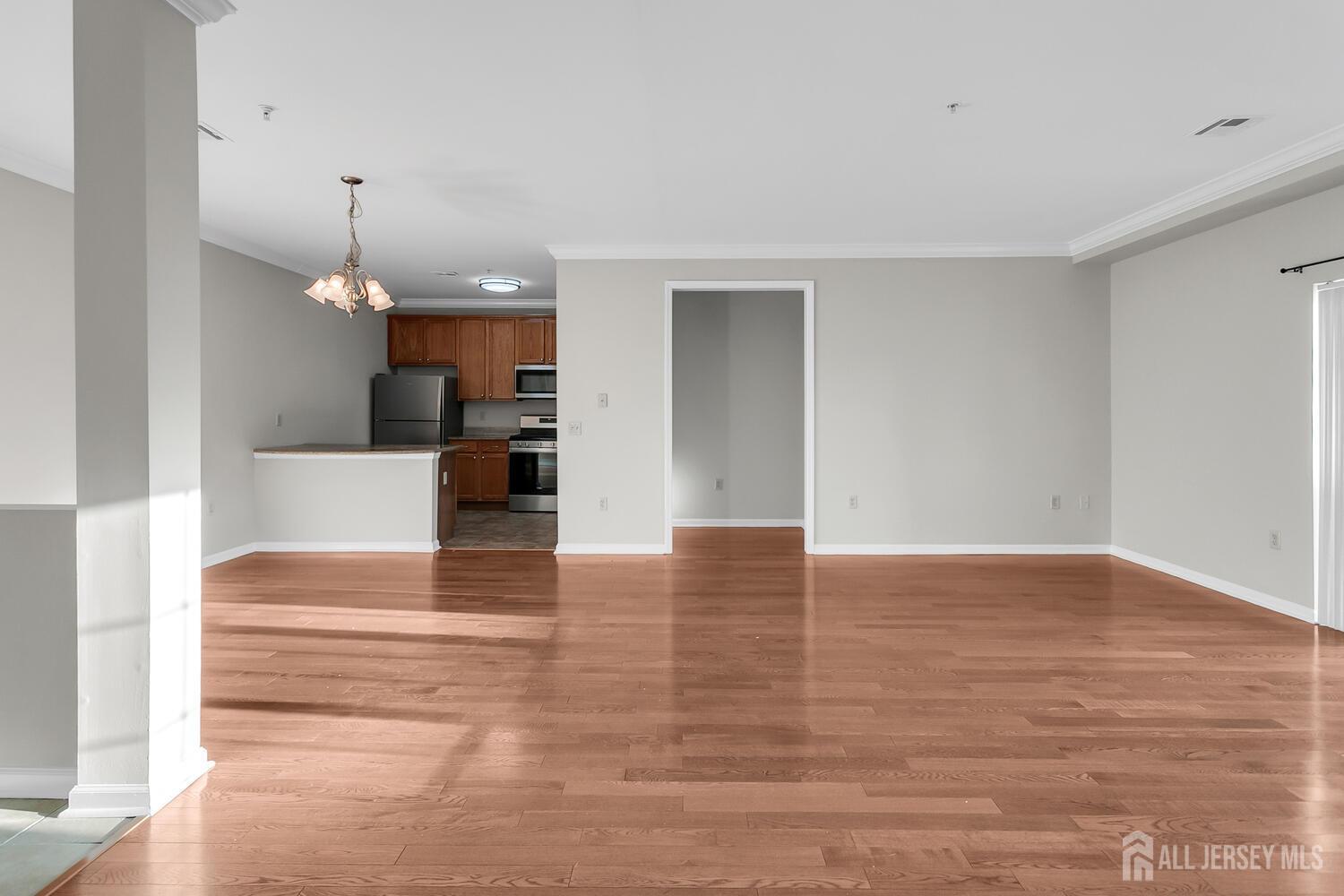 325 Regency Place Woodbridge, NJ 07095 - Photo 9 of 30 a view of empty room with wooden floor and kitchen view