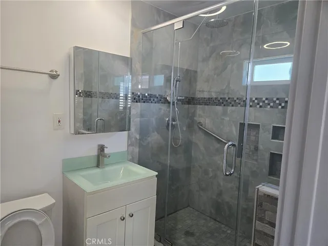 a bathroom with a shower sink vanity and mirror