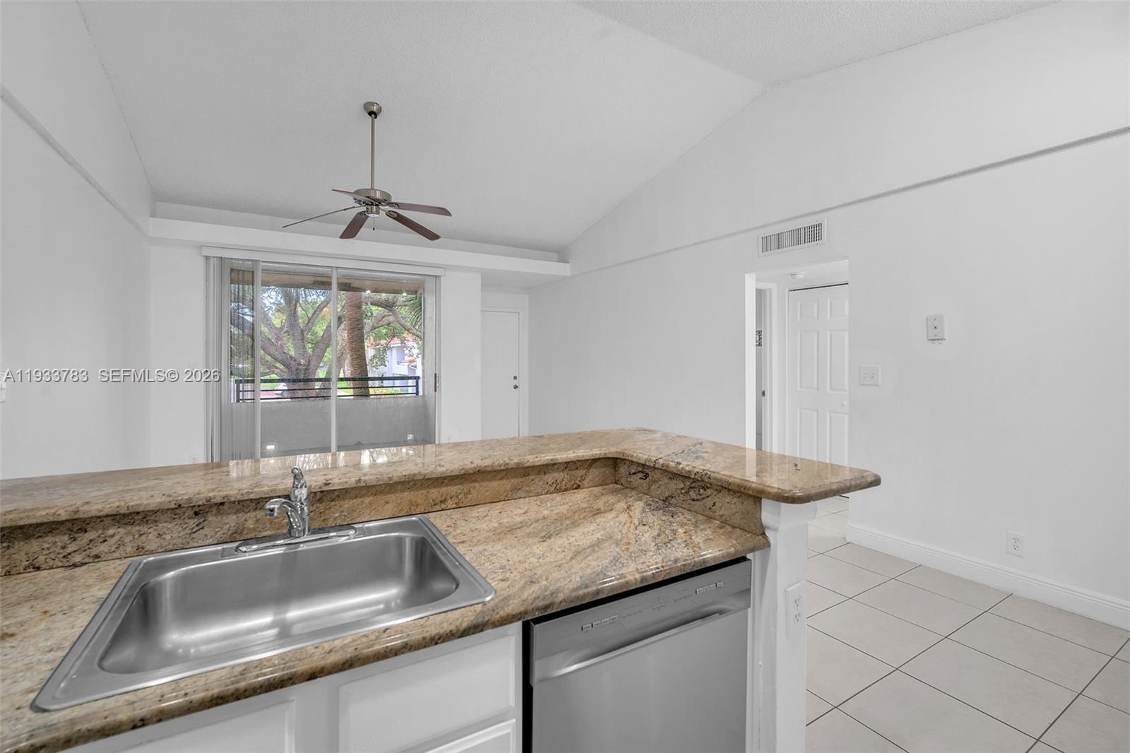 811 Lyons Road, Unit 20203 Coconut Creek, FL 33063 - Photo 2 of 21 a kitchen with granite countertop a sink and a wooden floor