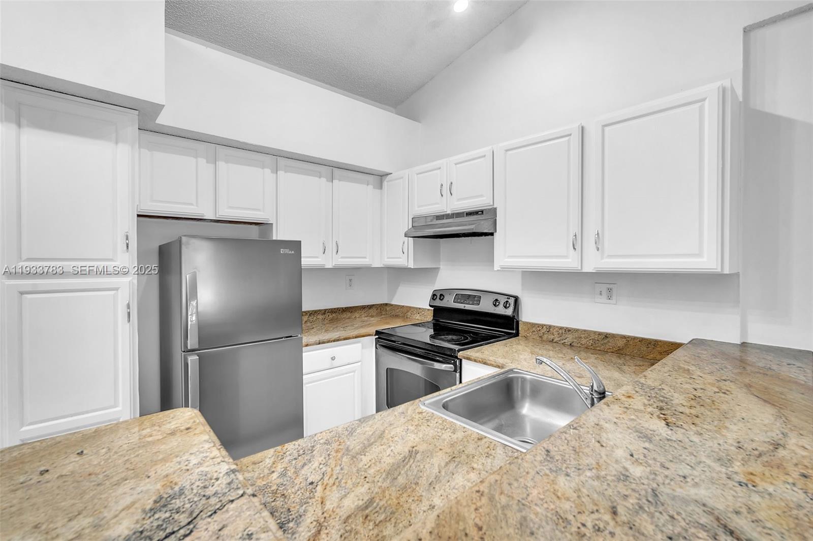 811 Lyons Road, Unit 20203 Coconut Creek, FL 33063 - Photo 3 of 23 a kitchen with granite countertop a refrigerator sink and cabinets