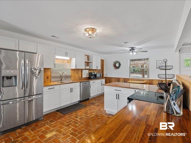 4650 Wiggins Lane Wilmer, AL 36587 - Photo 11 of 66 Kitchen featuring wooden counters, appliances with stainless steel finishes, white cabinets, a wainscoted wall, and wood walls