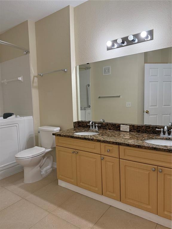 3725 Conroy Road, Unit 2127 Orlando, FL 32839 - Photo 17 of 30 a bathroom with a granite countertop toilet a sink and a mirror