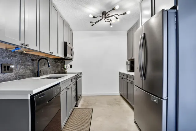 a kitchen with stainless steel appliances granite countertop a refrigerator a sink a stove and dishwasher