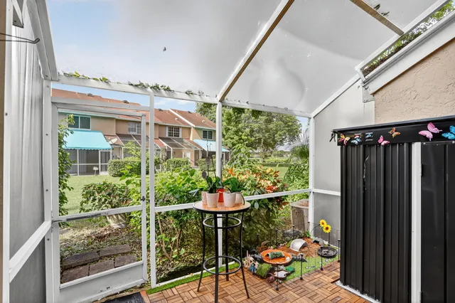 a balcony with table and chairs and potted plants