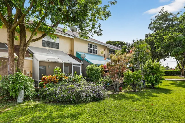 a view of a white house with a big yard and potted plants