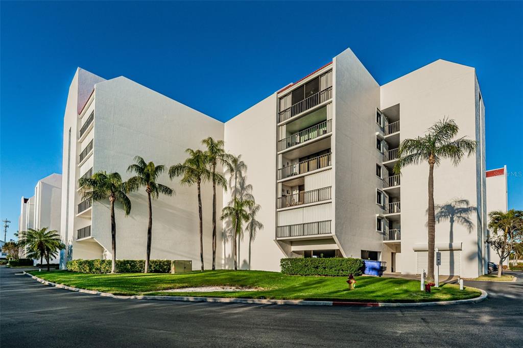 19111 Vista Bay Drive, Unit 211 Indian Shores, FL 33785 - Photo 60 of 62 a front view of multi story residential apartment building with yard and traffic signal