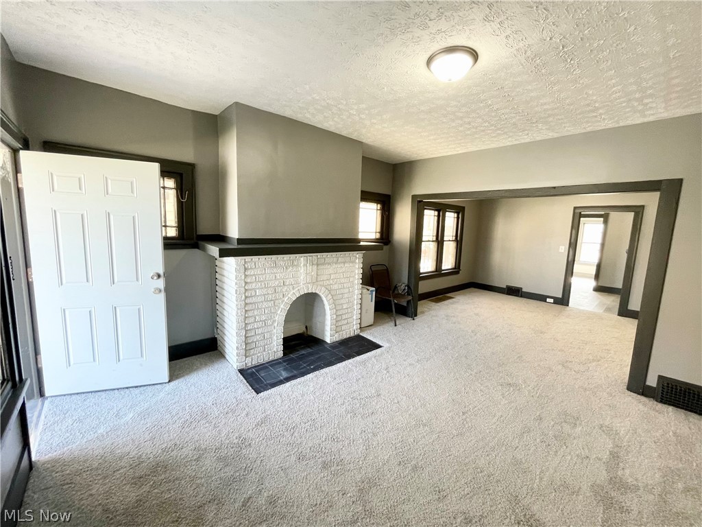 1756 Noble Road Cleveland, OH 44112 - Photo 2 of 28 1st Floor unit. Living room featuring a textured ceiling, carpet, and a brick fireplace