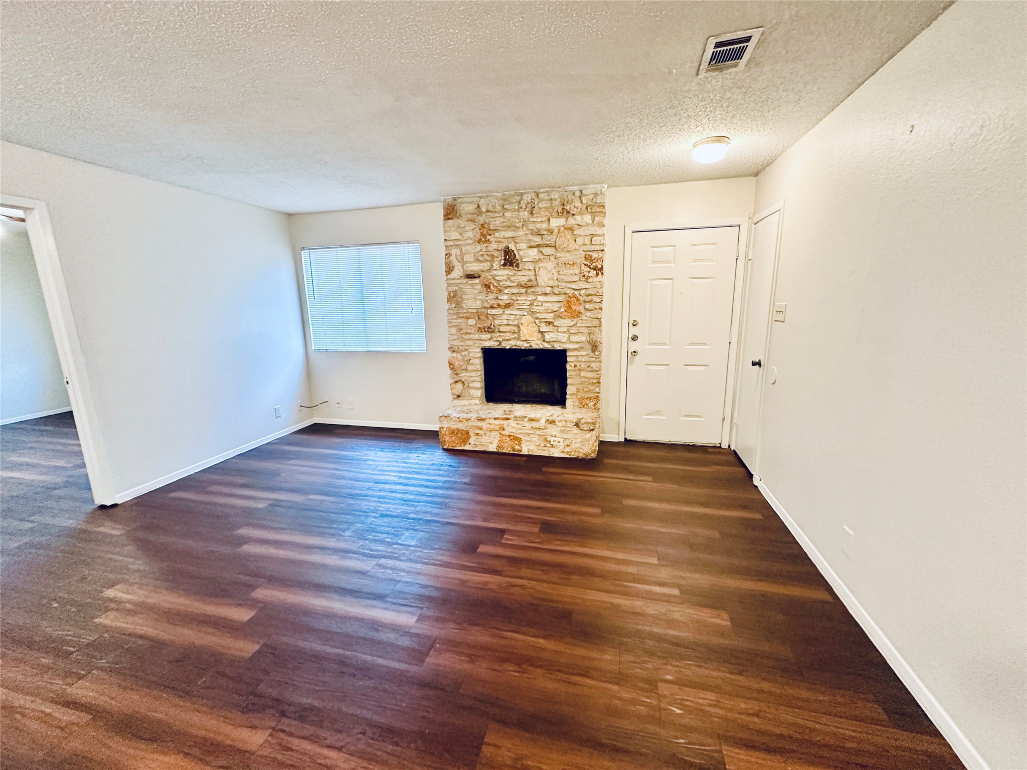 12505 Turtle Rock Road, Unit A Austin, TX 78729 - Photo 13 of 38 A cozy living space features rich wood flooring and a charming stone fireplace, perfect for intimate gatherings.