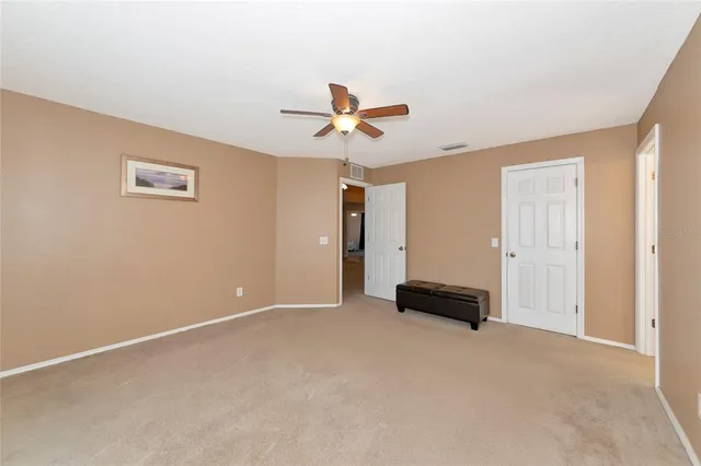 an empty room with closet and a ceiling fan