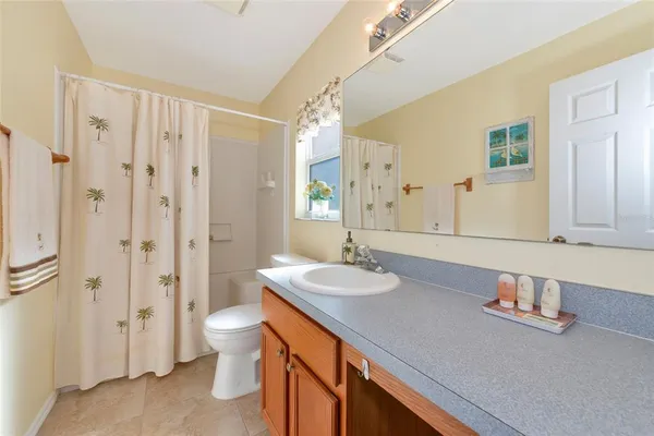 a spacious bathroom with a granite countertop sink a toilet a mirror and shower