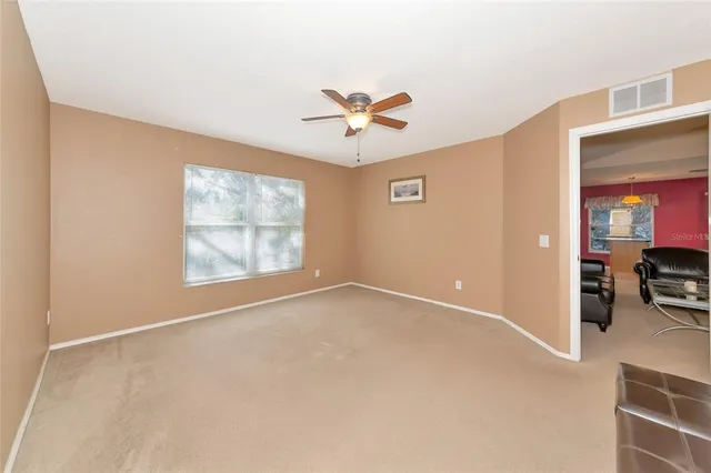 an empty room with windows and a ceiling fan