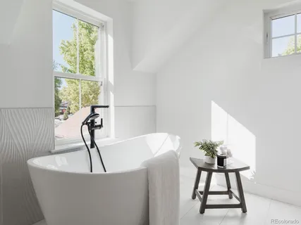 a white bath tub sitting in a bathroom next to a window