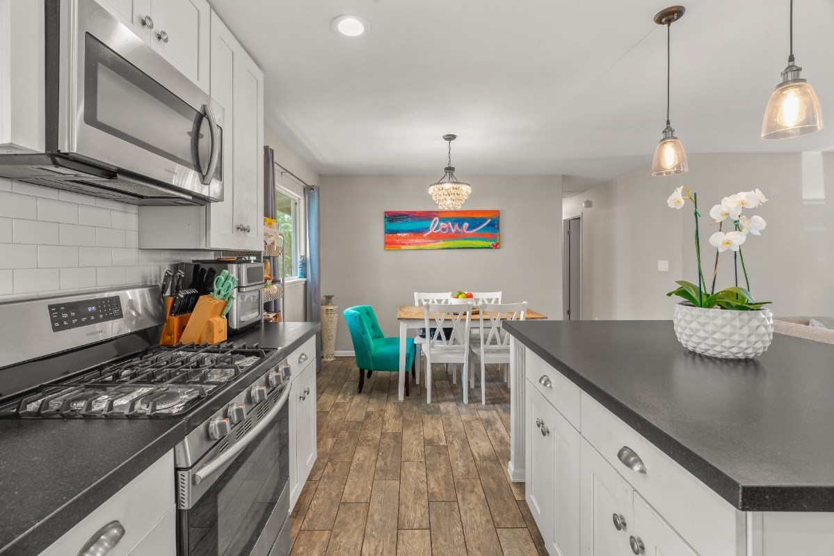 6391 Puupilo Road, Unit B Kapaa, HI 96746 - Photo 3 of 30 a kitchen with stainless steel appliances granite countertop a stove top oven a dining table and chairs with wooden floor