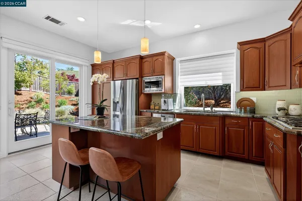 a kitchen with stainless steel appliances granite countertop a refrigerator a sink dishwasher a stove and a refrigerator