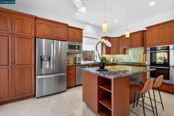 a kitchen with stainless steel appliances granite countertop a refrigerator a stove a sink and a refrigerator