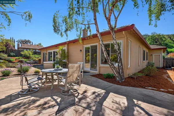 a view of a patio with table and chairs potted plants and large tree