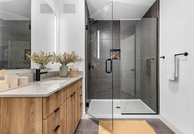 a bathroom with a granite countertop sink a mirror and shower