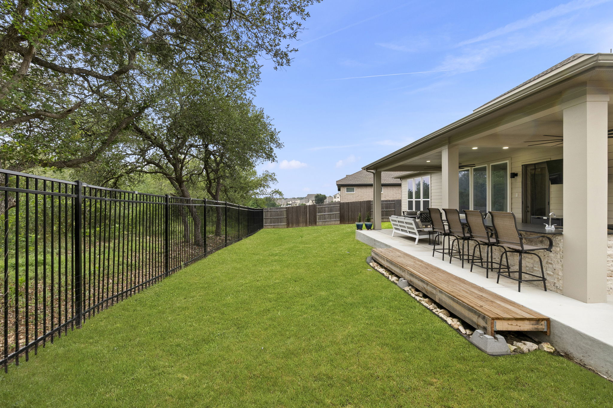 460 Constitution Way Kyle, TX 78640 - Photo 35 of 40 Expansive backyard featuring a manicured lawn, a black wrought iron fence, and mature trees along the property line