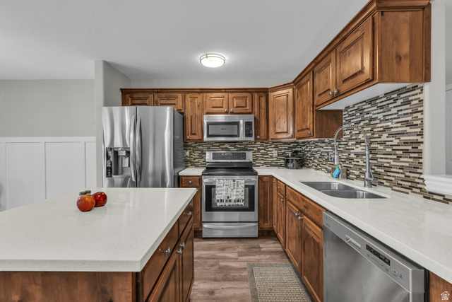 905 South Main Street, Unit G Layton, UT 84041 - Photo 4 of 36 Kitchen with stainless steel appliances, light stone counters, a center island, light wood-type flooring, and brown cabinetry