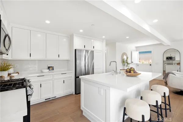 a kitchen with stainless steel appliances a sink a stove a refrigerator cabinets and chairs