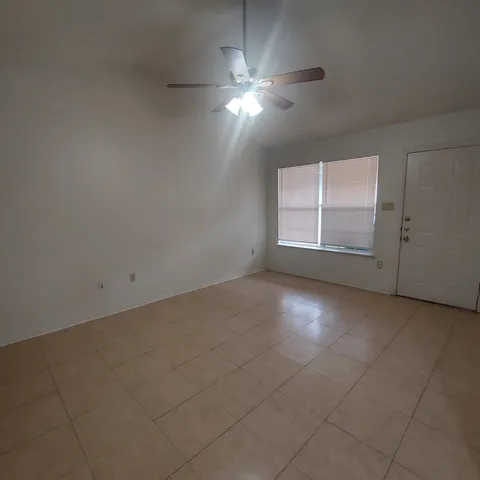 an empty room with a ceiling fan and window