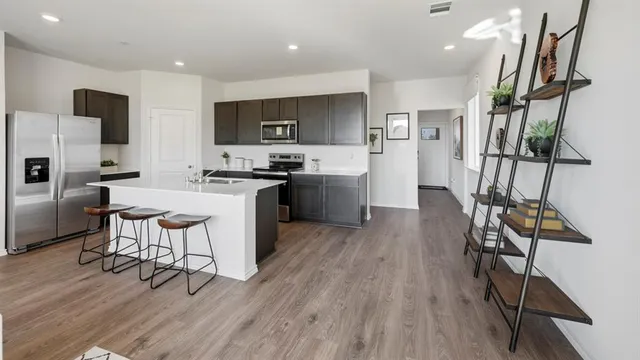 a kitchen with stainless steel appliances a refrigerator a stove a sink dishwasher and a dining table with wooden floor