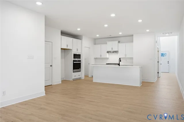 a view of kitchen with kitchen island white cabinets and stainless steel appliances