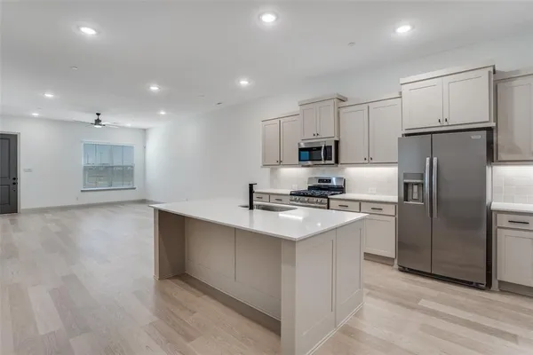 a kitchen with kitchen island a refrigerator sink and cabinets