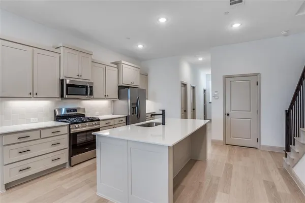 a kitchen with stainless steel appliances granite countertop a sink stove refrigerator and cabinets